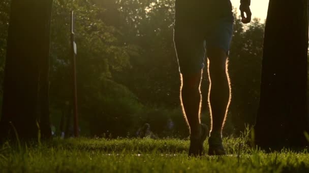 Super slow motion video van zomer zonsondergang park en runner draait op de camera — Stockvideo