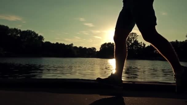 スローモーション ステディカム クリップ。堤防に沿って実行し始めて夕日公園ランナー — ストック動画