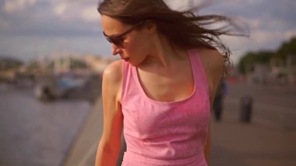 Menina morena bonita em vestido rosa em pé no dique do rio Moscou. Lento movimento clipe steadicam — Vídeo de Stock