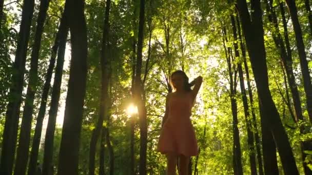 Chica morena delgada en vestido rosa camina en la cámara en el bosque. Clip de Steadicam — Vídeo de stock