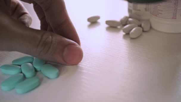 Man plukken een blauwe pil en onderzoekt het met vergrootglas. Close-up shot — Stockvideo