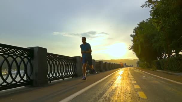 Desportista em roupas azuis correndo no dique do pôr-do-sol de verão em Moscou. Super câmera lenta steadicam tiro a 240 fps — Vídeo de Stock