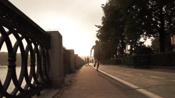 Hombre corriendo en el terraplén del atardecer de verano, Moscú. Colores cálidos blanqueados. Super cámara lenta steadicam disparo a 240 fps — Vídeo de stock