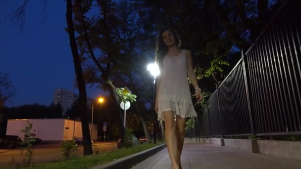 Όμορφη μελαχρινή κοπέλα περπάτημα στο κάμερα στο δρόμο steadicam νύχτα 4k πυροβόλησε — Αρχείο Βίντεο