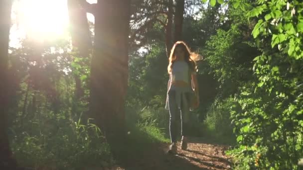 Chica morena caminando hacia la cámara en el bosque de coníferas puesta de sol. Zoom de disparo en cámara lenta — Vídeo de stock