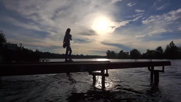 Silhouet ol lone slanke meisje lopen op kleine pier. Breed slow-motion shot — Stockvideo