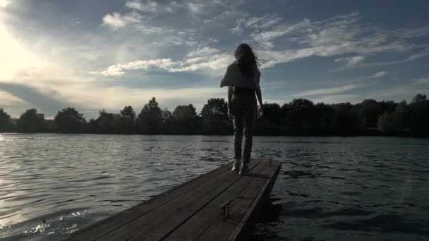 Mooi meisje lopen langs de smalle houten pier. Breed slowmotion pan schot — Stockvideo