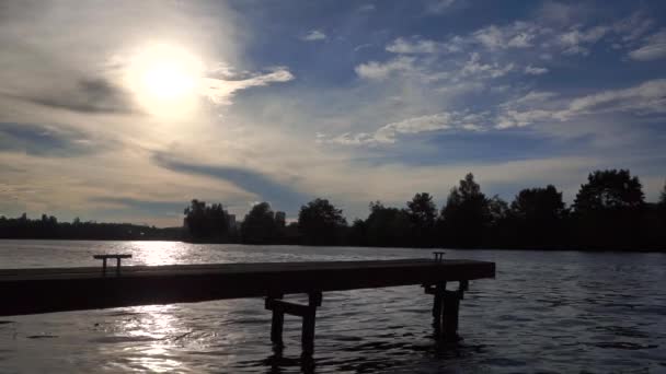 Silhouette del piccolo molo del fiume contro il sole della sera. Colpo largo, rallentatore — Video Stock