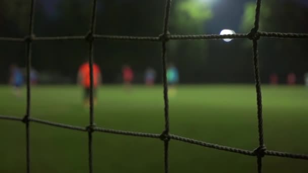 Evening football game slow motion bokeh video. View through mesh — Stock Video