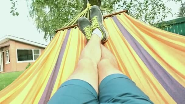 Jambes de l'homme balançant dans hamac vidéo 4K, couleurs blanchies — Video