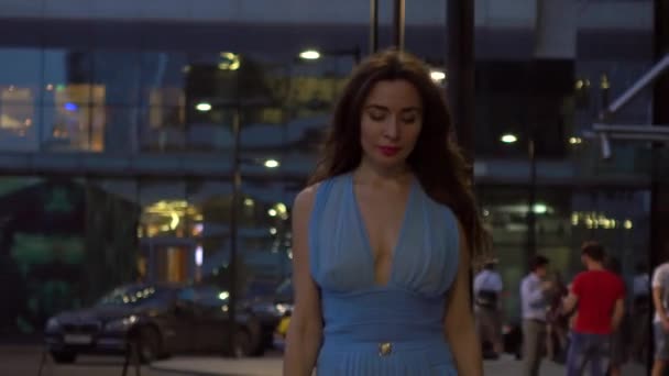Bella ragazza bruna in abito blu che cammina per strada di notte, clip 4K — Video Stock
