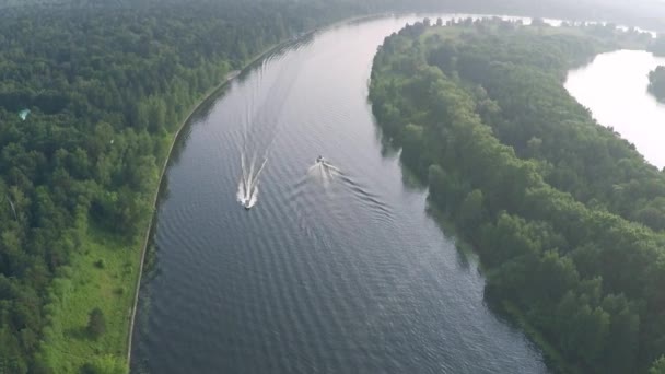 Antenne tilt shot van twee motorboten varen langs de rivier — Stockvideo