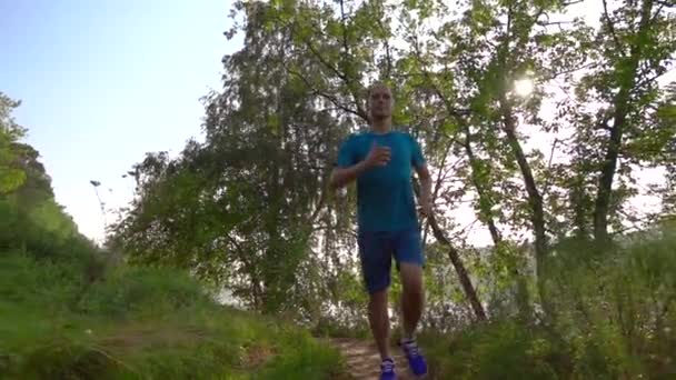 Super cámara lenta steadicam video de corredor más masculino con un reloj inteligente corriendo en el bosque, 240 fps — Vídeos de Stock