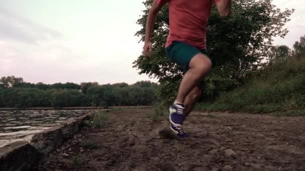 Super slow motion steadicam video of man in red running on sandy riverside, 240 fps — Stock Video