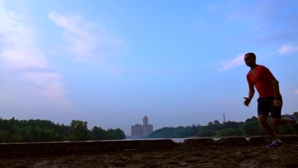 Super slow motion steadicam clip of man in red running on sandy riverside, 240 fps — Stock Video