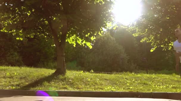 Steadicam suivi vidéo de l'homme athlétique en t-shirt blanc courir dans le parc contre le soleil et les arbres, super ralenti, 240 ips — Video