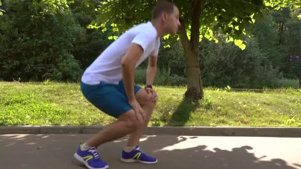 Erkek runner bağcıklarımı bağlar ve park sokakta çalışmaya başlar. 4 k steadicam izleme atış — Stok video
