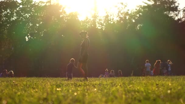 Moskau, russland - 8. august 2016. glückliche familie spazieren auf dem gras im sonnenuntergangspark und fotografieren mit handy. 4k-Video — Stockvideo