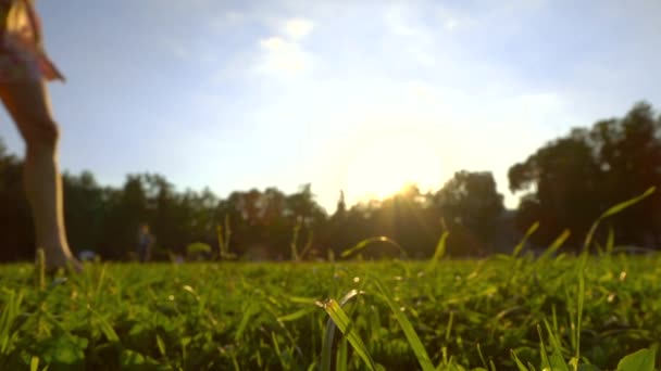 Super slow motion klipp av attraktiva flicka kör barfota på gräset håller hennes skor i handen — Stockvideo