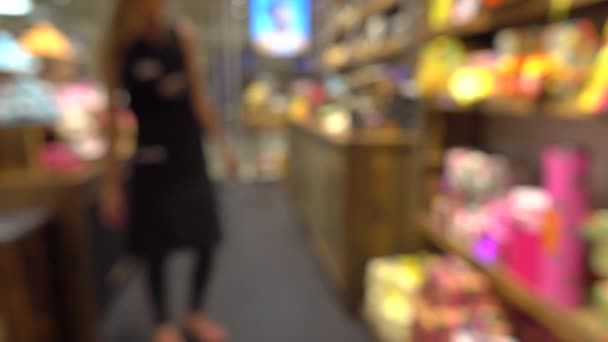 Assistante de magasin floue décorant vitrine dans le magasin de cosmétiques. 4K fond bokeh vidéo — Video