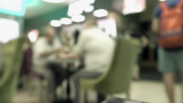 Неузнаваемые люди едят фаст-фуд в торговом центре. 4K фоновое видео боке — стоковое видео