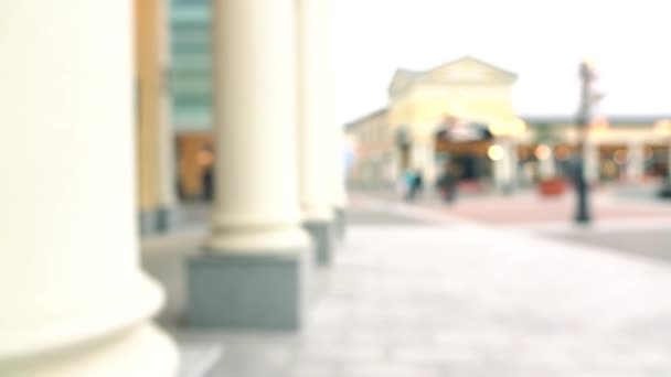 Ragazza bruna sottile sfocata in jeans che cammina con i suoi acquisti per colonne. 4K bokeh video di sfondo — Video Stock