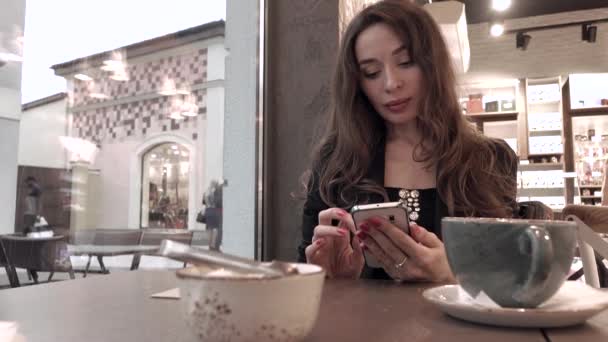 Menina morena bonita usando seu telefone celular no café. Vídeo 4K — Vídeo de Stock