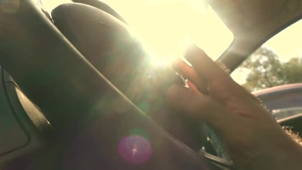 Conductor feliz tocando sus dedos en el volante contra el sol abrasador, colores cálidos. Vídeo 4K — Vídeos de Stock