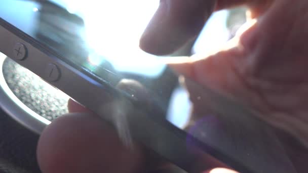 Pollice dell'uomo che tocca un touchscreen di uno smartphone contro il sole. Video macro DOF 4K poco profondo — Video Stock