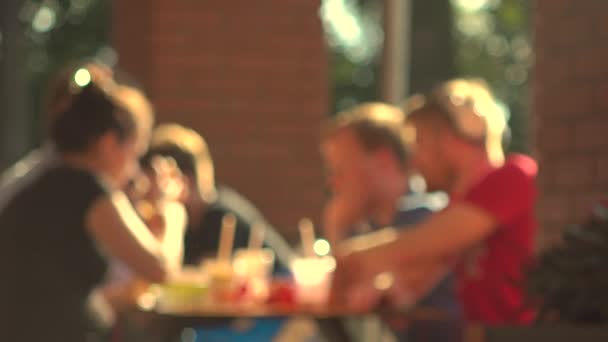 Jóvenes borrosos comiendo comida rápida al aire libre. 4K fondo de vídeo bokeh — Vídeos de Stock
