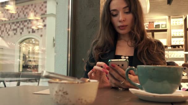 Piękna młoda kobieta, jej smartfona w kawiarni. wideo 4k — Wideo stockowe