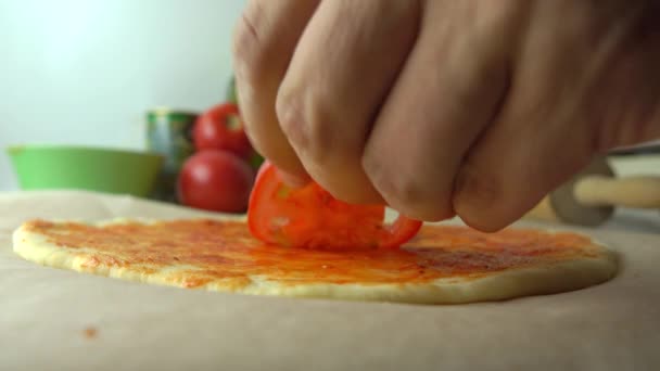 Człowiek, wprowadzenie plastry pomidora nad pizza podstawowa. Gotowanie, część zestawu. 4k z bliska strzał — Wideo stockowe