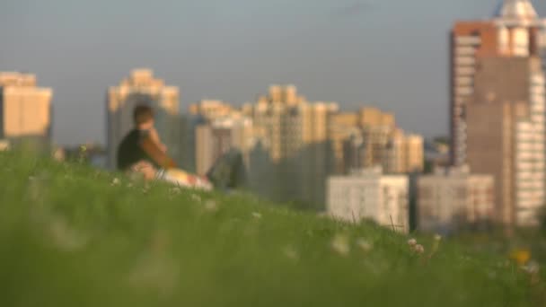 Jovem guitarrista irreconhecível no parque da cidade contra o urbanscape. 4K plano de fundo — Vídeo de Stock