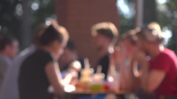 Молоді люди їдять фаст-фуди на відкритому повітрі. 4K фонове відео боке — стокове відео