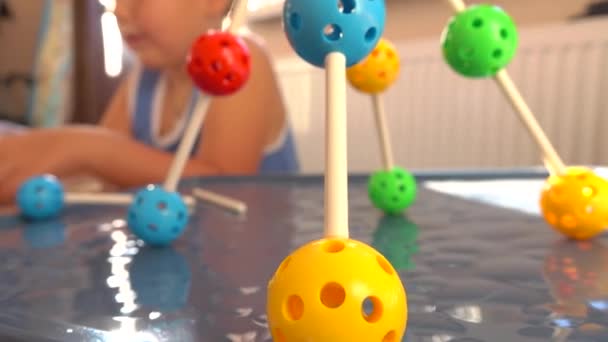 Niño jugando con el juego de construcción de plástico de colores. Modelos moleculares. 4K tiro de cerca — Vídeo de stock