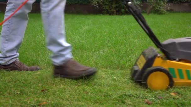 Homme coupe herbe avec tondeuse à gazon jaune. Profil 4K tir au ralenti — Video