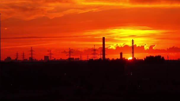 Industrial orange sunset. Sun goes down behind pipes and power pylons. 4K real time long shot — Stock Video