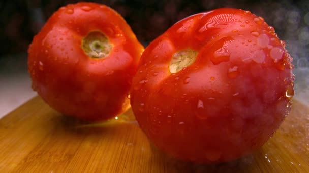 Dois tomates molhados maduros em tábua de corte de madeira. Drenagem gotas de água. 4K close up de vídeo — Vídeo de Stock