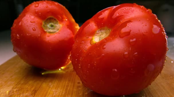 Tomates rojos sobre tabla de cortar de madera rociados con agua. 4K tiro en tiempo real — Vídeos de Stock