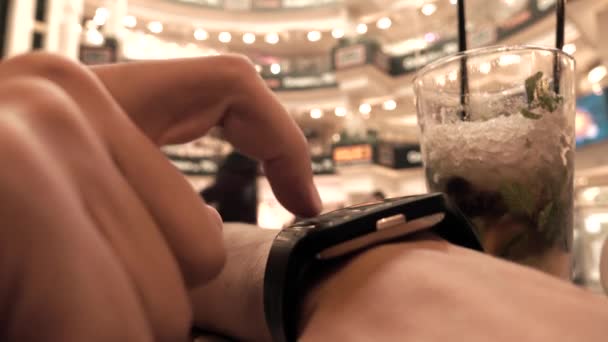 Ο άνθρωπος χρησιμοποιώντας έξυπνο ρολόι του σε μια καφετέρια. 4k, κοντινό πλάνο — Αρχείο Βίντεο
