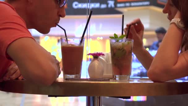 Echtpaar met hun koude dranken in een winkelcentrum café tegen grote raam. Mobiele telefoon verslaving. 4k schot — Stockvideo