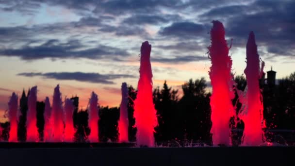 Fuentes modernas del parque iluminado rojo contra el cielo del atardecer. Iluminación led arquitectónica. Vídeo en cámara lenta — Vídeo de stock