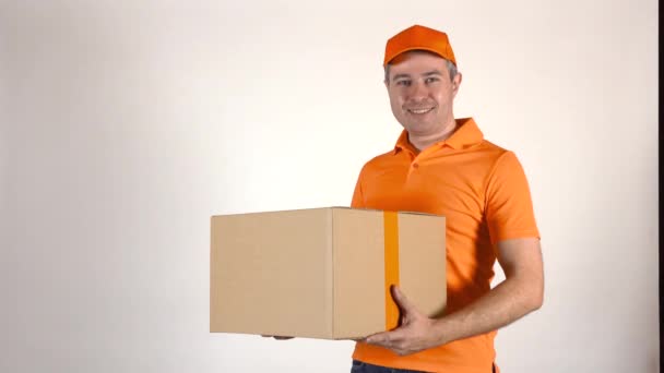 Livraison homme en uniforme orange livrant une grande boîte. Arrière-tour gris clair, prise de vue studio 4K — Video