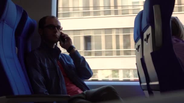 Man in glazen praten op zijn telefoon in een moderne trein. 4k video — Stockvideo