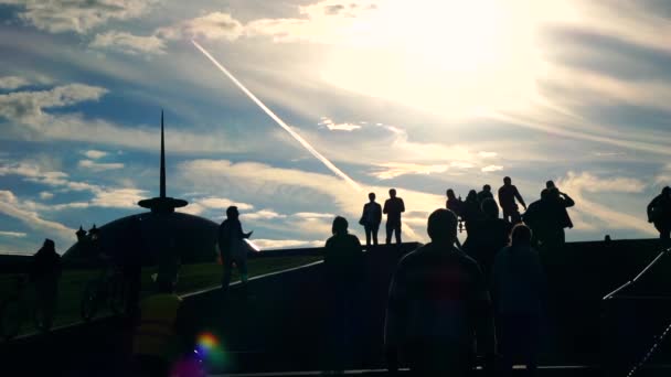 Sylwetki ludzi chodzących na górze i na dole przed niebo i odległych latający samolot pasażerski. Slow motion shot — Wideo stockowe