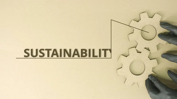 Rodas de engrenagem de papelão e texto de sustentabilidade na mesa — Fotografia de Stock
