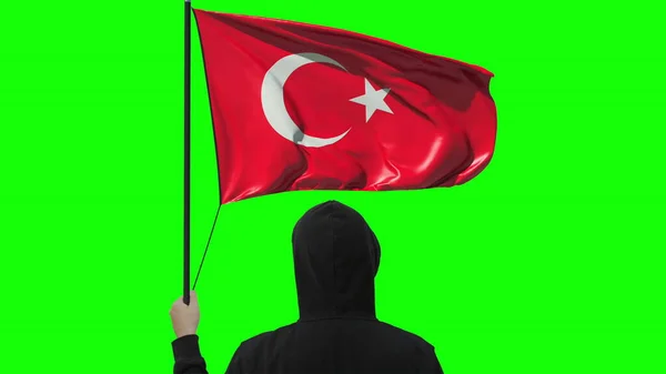 Unknown man holds waving flag of Turkey, isolated on green background — Stock Photo, Image