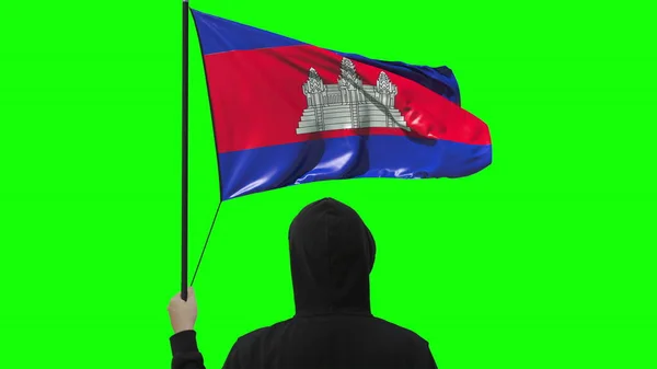 Homem desconhecido segura bandeira acenando do Camboja, isolado em fundo verde — Fotografia de Stock