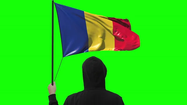 Bandera ondeante de Rumania y hombre desconocido vestido de negro, aislado sobre fondo verde — Foto de Stock