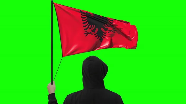 Unbekannter hält schwenkende albanische Flagge auf grünem Hintergrund — Stockfoto